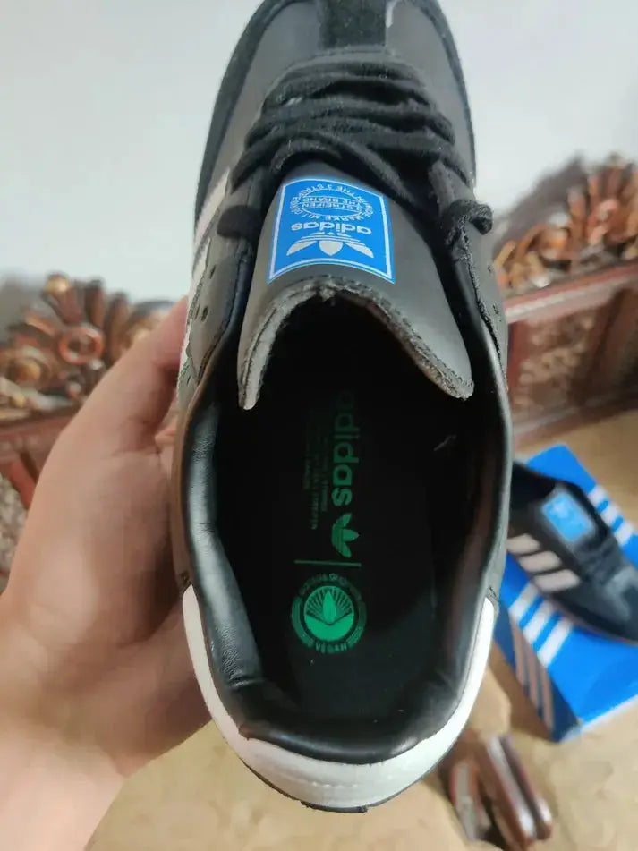 "Adidas Samba OG Black sneaker inside view with logo and packaging box in background"