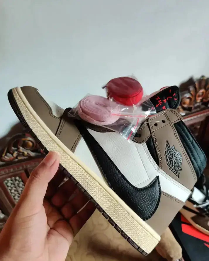 Travis Scott X Nike Air Jordan 1 High Cactus Jack Mocha sneaker being held, showcasing unique mocha and black colorway.